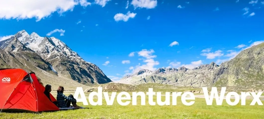 Campsite with tents overlooking green mountains, Adventure Worx branded banner