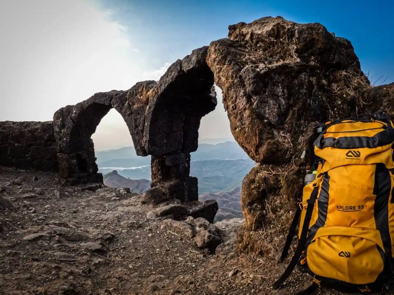 Rucksack bag resting on rocks near a coastal rock arch