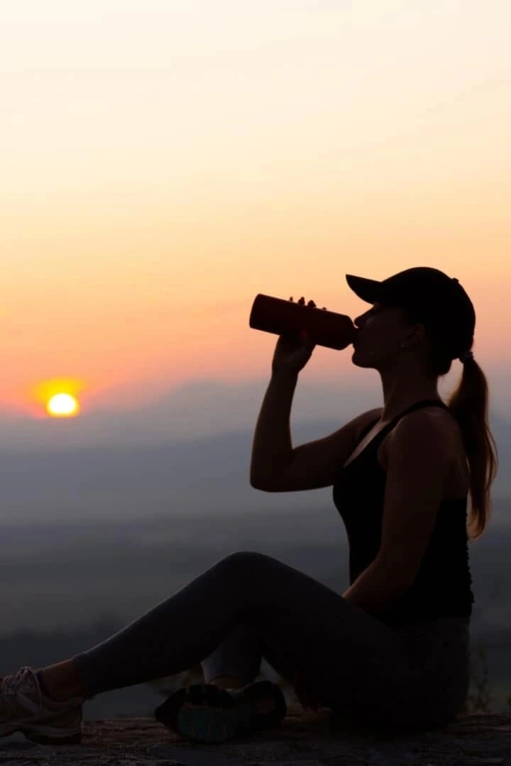 Trekker drinking from an insulated water bottle in cold conditions